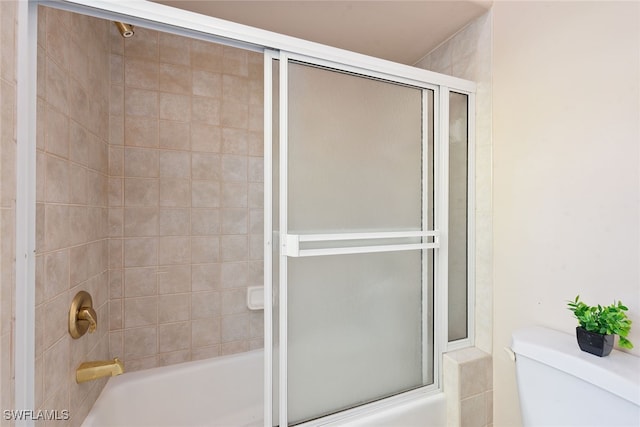 bathroom featuring combined bath / shower with glass door and toilet