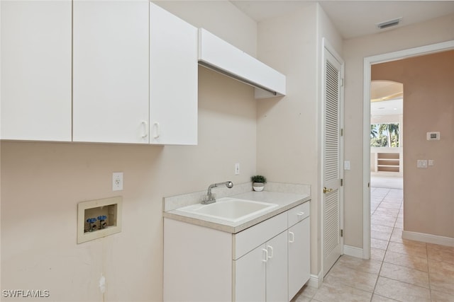 washroom featuring hookup for a washing machine, sink, light tile patterned floors, and cabinets