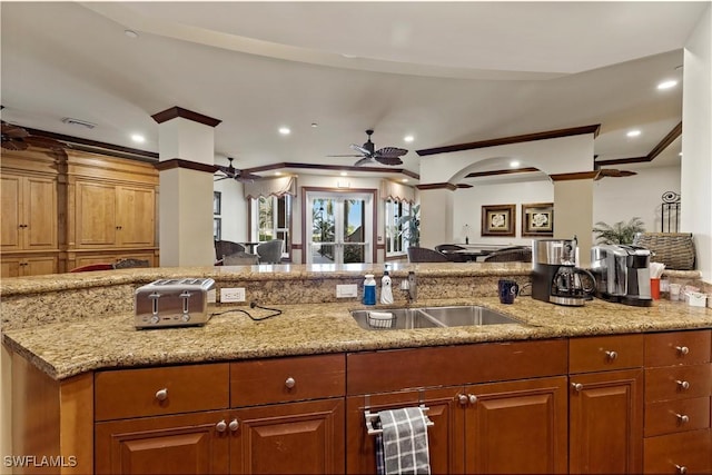 kitchen with ceiling fan, light stone countertops, and sink