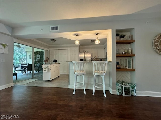 kitchen featuring a kitchen breakfast bar, kitchen peninsula, wood-type flooring, decorative light fixtures, and stainless steel refrigerator with ice dispenser