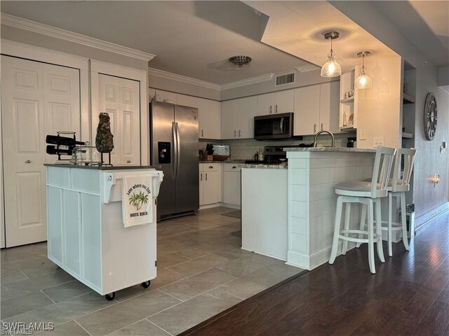 kitchen with white cabinets, pendant lighting, kitchen peninsula, hardwood / wood-style flooring, and stainless steel appliances