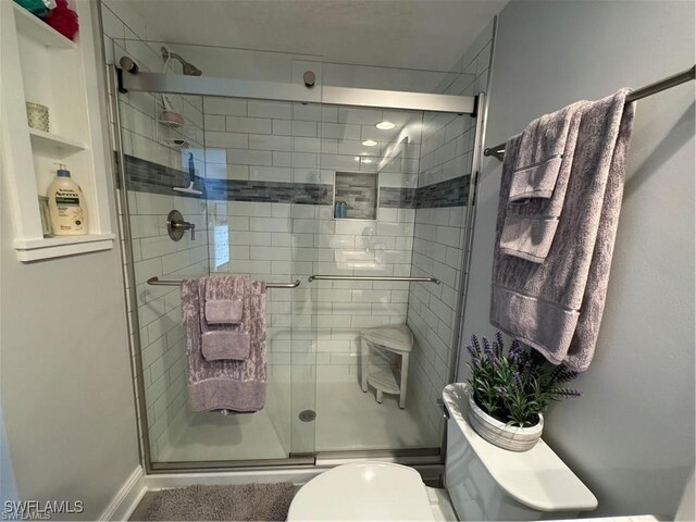 bathroom featuring toilet and a shower with shower door