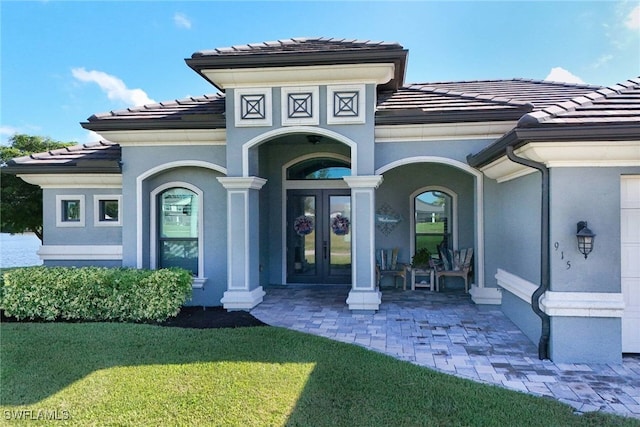 entrance to property featuring a lawn and french doors