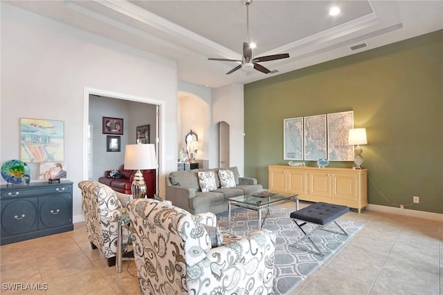 tiled living room with a tray ceiling and ceiling fan