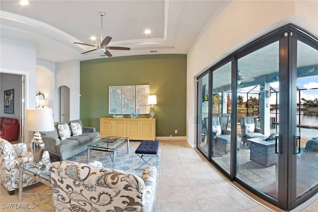 living room featuring light tile patterned floors, a tray ceiling, ceiling fan, and french doors