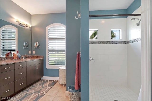 bathroom featuring a tile shower, vanity, tile patterned flooring, and a healthy amount of sunlight