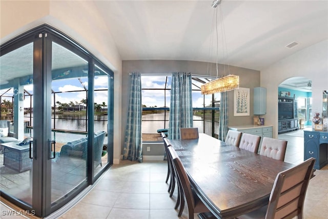 dining space featuring french doors, light tile patterned floors, vaulted ceiling, and a water view