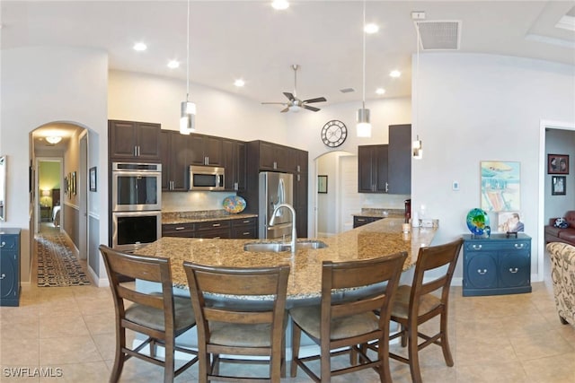 kitchen featuring ceiling fan, sink, kitchen peninsula, high vaulted ceiling, and appliances with stainless steel finishes