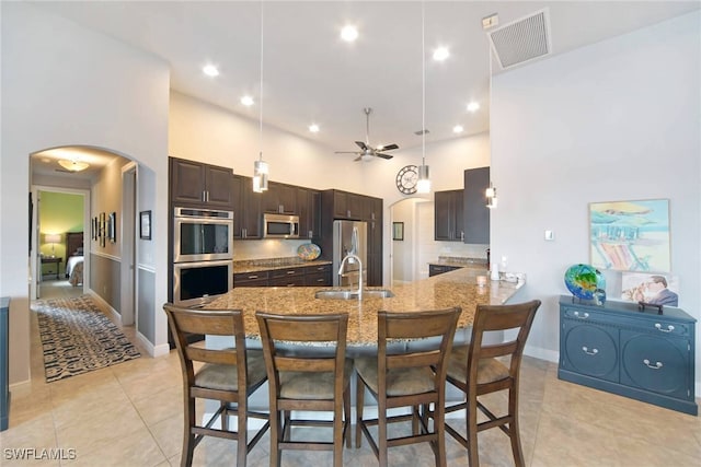 tiled dining area featuring ceiling fan, sink, and a high ceiling