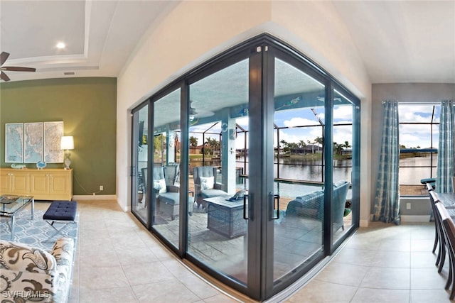 entryway featuring a water view, light tile patterned floors, lofted ceiling, ceiling fan, and french doors