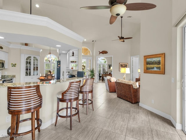 kitchen featuring light stone counters, stainless steel appliances, a high ceiling, and pendant lighting