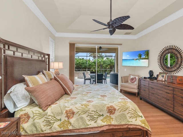 bedroom with a raised ceiling, hardwood / wood-style floors, access to exterior, ceiling fan, and crown molding