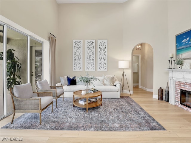 living room with a high ceiling, hardwood / wood-style floors, and a brick fireplace