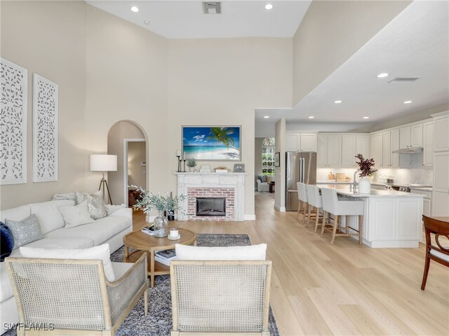 living room with a fireplace, a high ceiling, and light hardwood / wood-style flooring