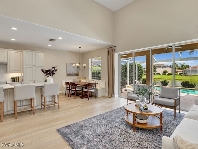 living room with a high ceiling, light hardwood / wood-style floors, and an inviting chandelier