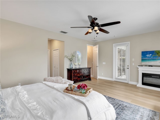 bedroom featuring ceiling fan, light wood-type flooring, and multiple windows