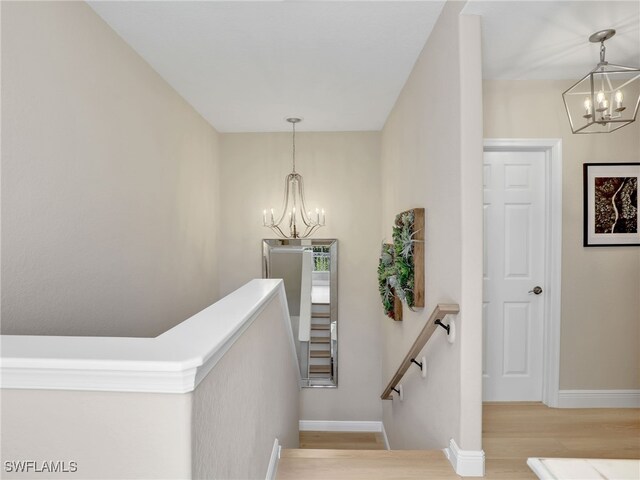 staircase featuring an inviting chandelier and hardwood / wood-style flooring