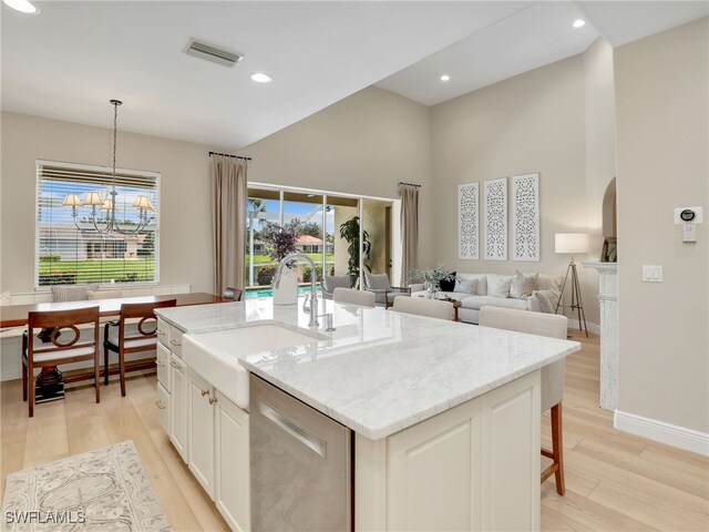 kitchen featuring an island with sink, dishwasher, light hardwood / wood-style floors, and pendant lighting