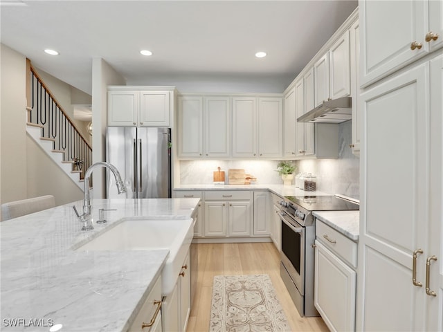 kitchen featuring appliances with stainless steel finishes, light stone countertops, light hardwood / wood-style flooring, and white cabinets