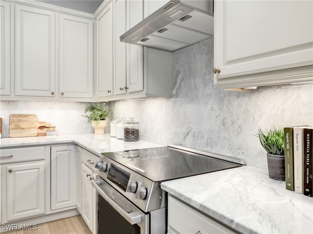 kitchen with range hood, white cabinets, light hardwood / wood-style flooring, and electric range