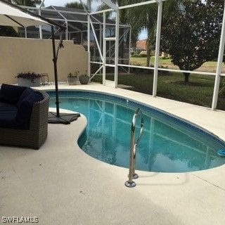 view of pool featuring glass enclosure and a patio area