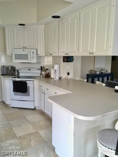 kitchen with white cabinets, kitchen peninsula, white appliances, and a breakfast bar