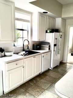 kitchen featuring white appliances, white cabinetry, and sink