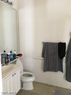 bathroom with tile walls, tile patterned floors, vanity, and toilet