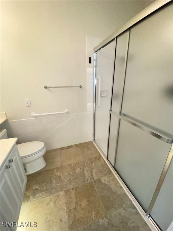 7617 Garibaldi Ct, Naples, FL 34114 - full bath featuring toilet, a stall shower, vanity, and tile walls