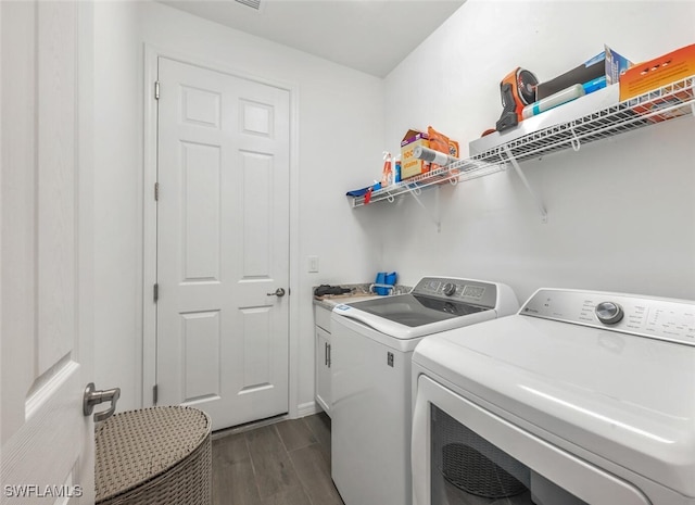 clothes washing area featuring cabinets, washing machine and clothes dryer, and dark hardwood / wood-style flooring