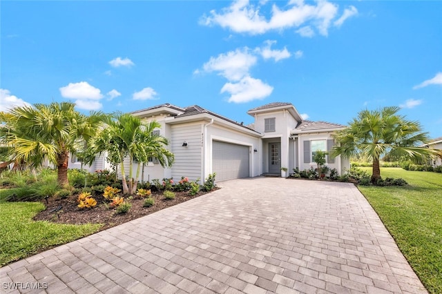 mediterranean / spanish-style house with decorative driveway, a garage, a front yard, and stucco siding