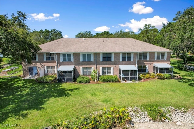 rear view of property featuring a lawn and a sunroom