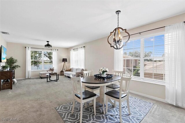 carpeted dining room with an inviting chandelier