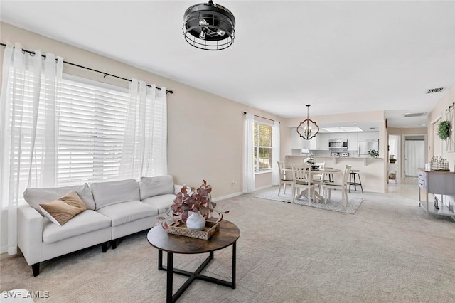 carpeted living room with a notable chandelier