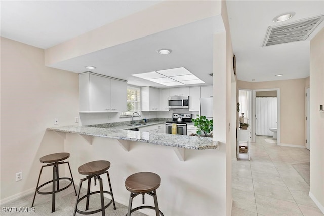 kitchen featuring light tile patterned flooring, sink, white cabinetry, kitchen peninsula, and stainless steel appliances