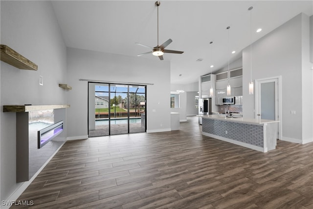 unfurnished living room with ceiling fan, high vaulted ceiling, and dark hardwood / wood-style floors