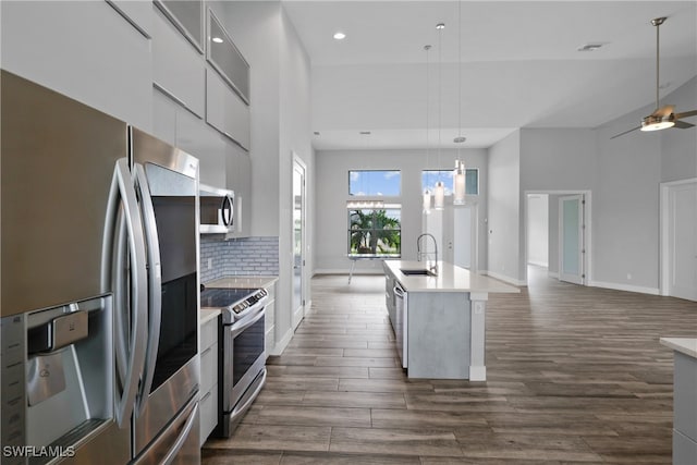 kitchen with white cabinetry, sink, dark wood-type flooring, an island with sink, and appliances with stainless steel finishes