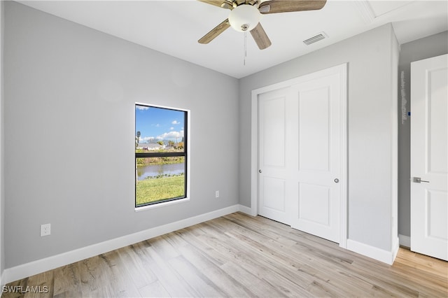 unfurnished bedroom with light hardwood / wood-style floors, ceiling fan, and a closet