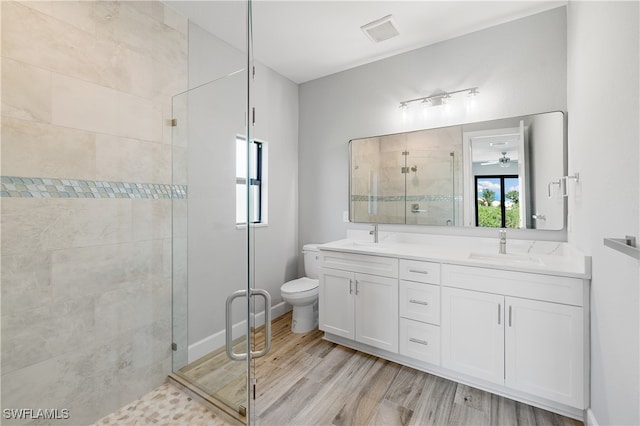 bathroom with vanity, wood-type flooring, ceiling fan, a shower with door, and toilet