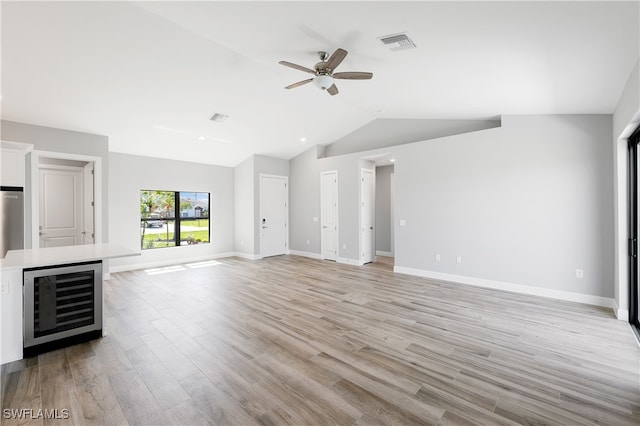 unfurnished living room featuring light hardwood / wood-style flooring, beverage cooler, vaulted ceiling, and ceiling fan