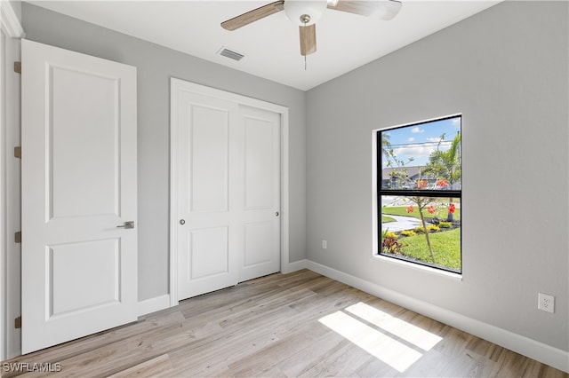 unfurnished bedroom featuring a closet, light wood-type flooring, and ceiling fan