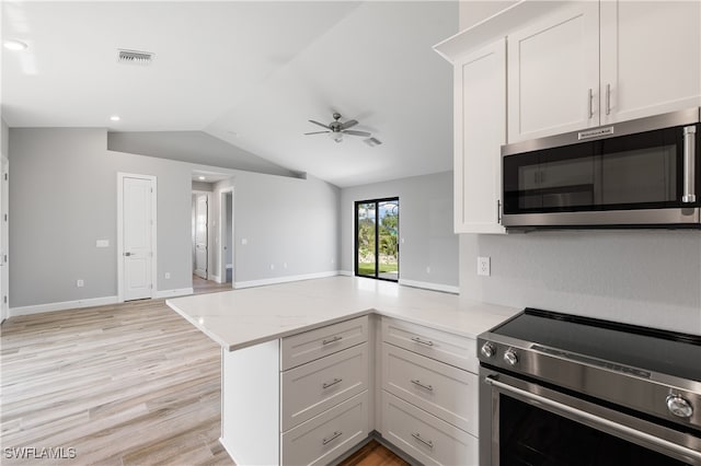 kitchen featuring vaulted ceiling, kitchen peninsula, appliances with stainless steel finishes, and white cabinetry