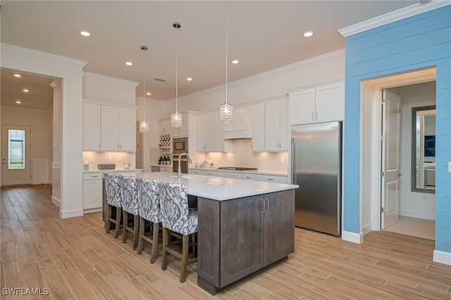 kitchen with built in appliances, light hardwood / wood-style flooring, and white cabinets