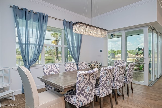 dining space with crown molding, light hardwood / wood-style flooring, and a chandelier