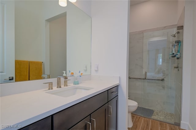 bathroom with a tile shower, vanity, toilet, and hardwood / wood-style flooring