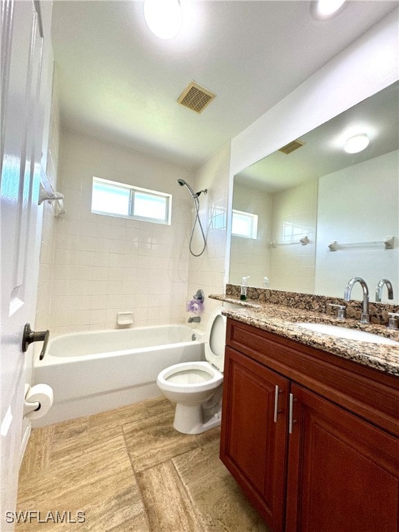 full bathroom featuring tile patterned floors, tiled shower / bath combo, toilet, and vanity