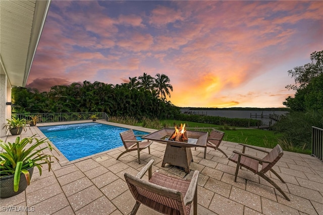 pool at dusk featuring a patio area and an outdoor fire pit