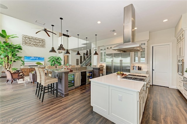 kitchen featuring island exhaust hood, white cabinetry, a large island, and appliances with stainless steel finishes