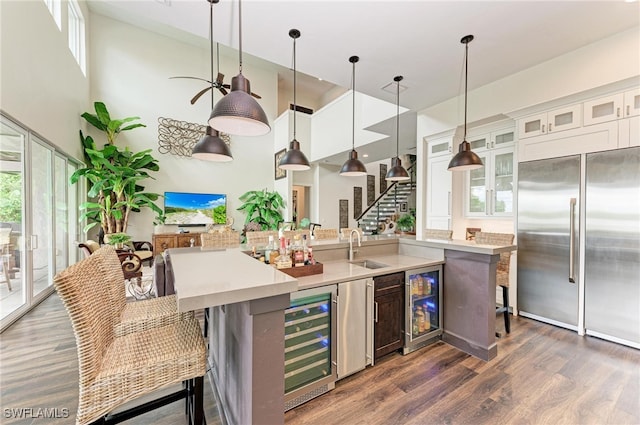 kitchen with stainless steel built in fridge, wine cooler, decorative light fixtures, white cabinetry, and dark hardwood / wood-style flooring