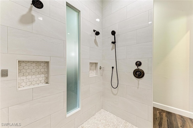 bathroom featuring a tile shower and wood-type flooring